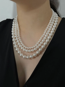 Elegant triple-layered white pearl necklace with gradient sizes on a model's neck