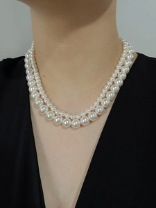 Close-up of elegant double-layer white pearl necklace worn on model for formal style