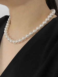 Detail of elegant white pearl necklace on model showing 8-10mm lustrous round pearls