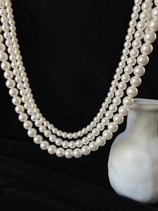 Detail of elegant three-layer white pearl necklace displayed on black velvet background