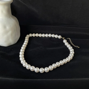 Elegant white round pearl necklace with gold lobster clasp on luxurious black velvet