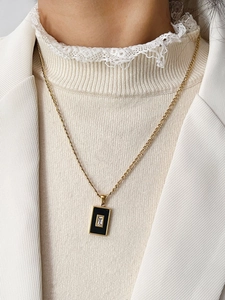 Detail van een gouden Figaro-schakelketting met zwarte emaille hanger en zirkonia steen