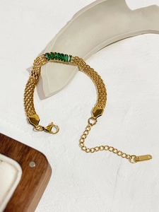 Primer plano detallado de pulsera de eslabones dorados con circonitas verde esmeralda y cierre