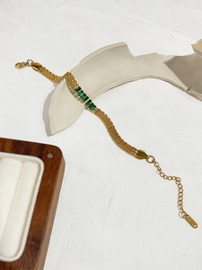 Detalle de pulsera de cadena bañada en oro de 18K con piedras preciosas verdes rectangulares