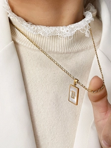 Gedetailleerde close-up van een gouden rechthoekige hanger met parelmoer en zirkoon