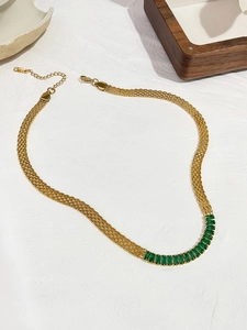 Detalle del collar de cadena dorada con una fila de circonitas verde esmeralda