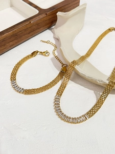 Detalle del conjunto de collar y pulsera de malla dorada con circonitas baguette