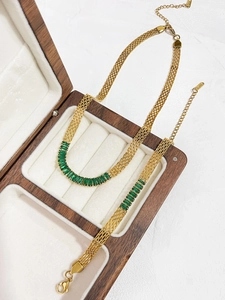 Detalle del conjunto de collar y pulsera de malla dorada con circonitas verdes en joyero