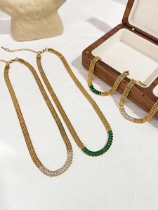 Detalle del conjunto de joyas de malla dorada con cristales baguette verdes y blancos