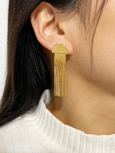 Détail de boucles d'oreilles demi-cercle dorées avec franges métalliques sur un modèle