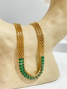 Detalle de collar de cadena trenzada dorada con piedras preciosas verdes rectangulares