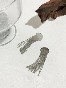 Détail de boucles d'oreilles argentées minimalistes demi-rondes avec longues franges