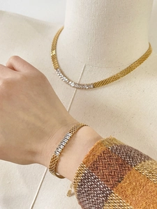 Detalle del conjunto de collar y pulsera de malla dorada con circonitas blancas