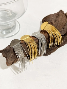 Détail des boucles d'oreilles à pampilles en or et argent sur des supports en bois