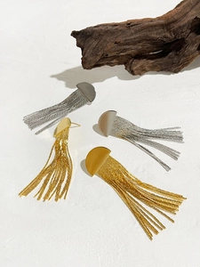 Détail de boucles d'oreilles à pampilles dorées et argentées sur un fond de bois naturel