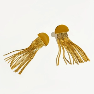 Boucles d'oreilles dorées en demi-cercle avec franges de chaînes métalliques sur fond blanc