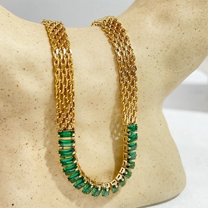 Collar de cadena de malla dorada con circonitas verdes en un soporte de busto cerámico