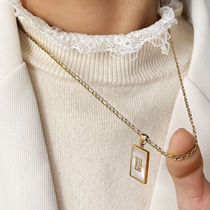 Gouden ketting met rechthoekige parelmoer hanger en zirkoon op een Figaro-ketting