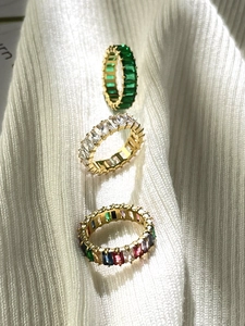 Detailaufnahme von 18K vergoldeten Ringen mit Smaragd-, klaren und bunten Zirkonsteinen