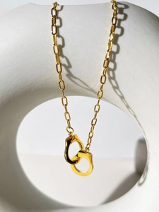 Detailed view of 18K gold handcuff link necklace draped on minimalist white display