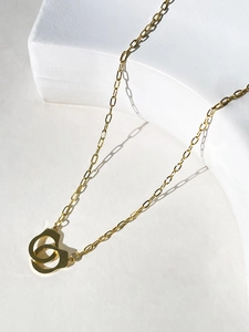 Macro view of 18K gold-plated handcuff pendant with paperclip chain on white stone