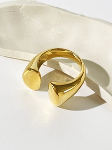 Detail eines 18K vergoldeten offenen Rings mit asymmetrischen Enden auf Steinboden