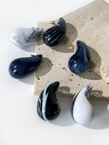 Detailed macro view of teardrop acrylic earrings with elegant marble patterns and metal pins
