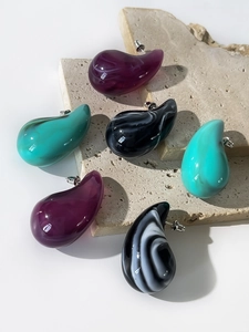 Macro detail of acrylic drop earrings with marble textures on a stone surface