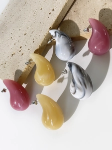 Macro shot of stylish resin teardrop earrings in pink, amber, and marble colors