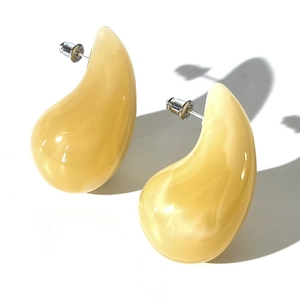 Close-up of yellow teardrop acrylic earrings with silver posts on white background