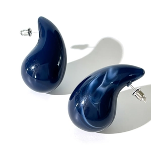 Macro detail of blue marbled acrylic waterdrop stud earrings with silver-tone metal posts