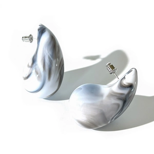 Macro detail of teardrop acrylic earrings with monochrome marble pattern and silver studs