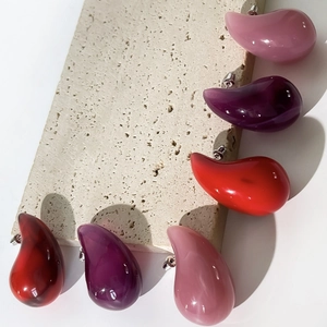 Three pairs of colorful teardrop acrylic stud earrings in red, purple, and pink