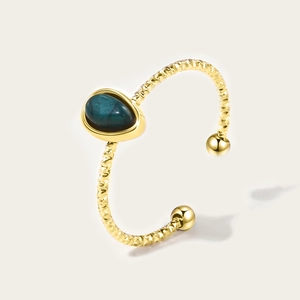 Detail van de druppelvormige turkooissteen op de 18K vergulde gedraaide touw ringband