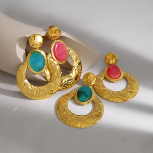 Detail van vintage gehamerde gouden oorbellen met kleurrijke ovale harsstenen en textuur