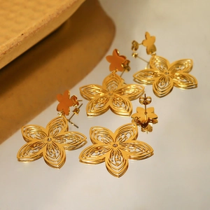 Macro detail of 18K gold-plated titanium steel hollow flower earrings with rich texture
