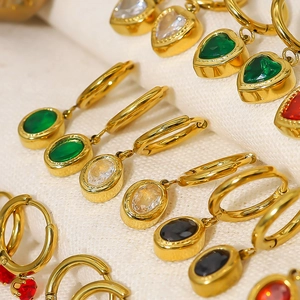 Macro shot of 18K gold earrings with colorful heart and oval zircon stone pendants