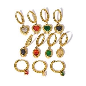 Macro detail of 18K gold earrings set with multicolored heart and oval zircon pendants