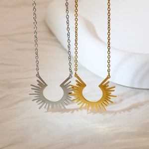 Gros plan de pendentifs soleil bohèmes en finitions or et argent sur tissu texturé
