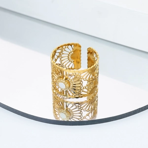 Detalle macro de anillo calado dorado con incrustación de nácar blanco sobre espejo