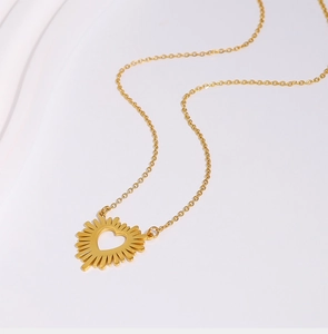 Detail of golden heart pendant with sunburst texture on a stainless steel cable chain
