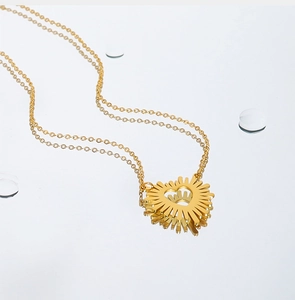 Macro detail of golden stainless steel sunburst heart pendant with elegant O-chain