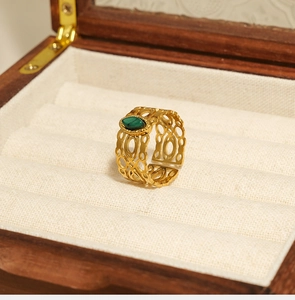 Detail van vintage gouden roestvrijstalen ring met hol snijwerk en groene stenen inleg