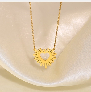 Detail shot of a golden heart sunburst necklace on elegant silk fabric background