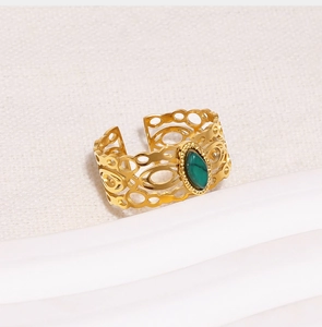 Detail van vintage gouden ring met marquise groene steen en opengewerkte textuur