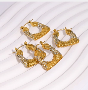 Detalle de pendientes de aro retorcidos en forma de U dorados con micro pavé de circonitas