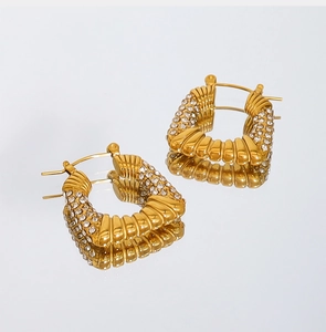 Detalle de pendientes de titanio chapados en oro con textura de rayas y circonitas