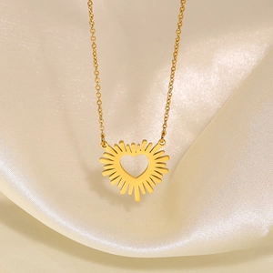 Stainless steel gold necklace with radiant sunburst heart pendant on silk background