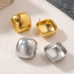 Macro-opname van minimalistische kubus oorknopjes met een geborsteld goud en zilver metaal