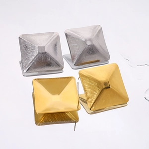 Detail van geborstelde 18k goud en zilveren piramide oorbellen met matte textuur